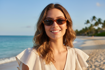 Femme portant des lunettes de soleil ovales UV400 sur une plage tropicale - Protection solaire premium